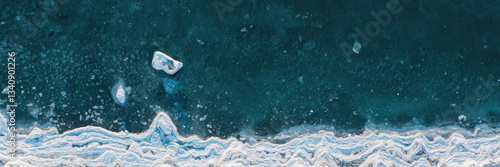 Obraz na płótnie Top view of the freezing sea. Winter aerial photograph of the icy coast and ice floes in sea water. Northern nature. Cold frosty winter weather. Arctic climate. Beautiful wide panoramic background. w salonie