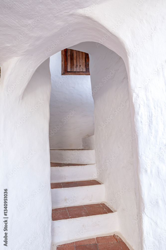 Minimalist stairway with a rustic arch and terra cotta tiles. The beautiful town of Binibeca on Menorca. Narrow streets and white walls of houses with wooden elements, Mediterranean architecture
