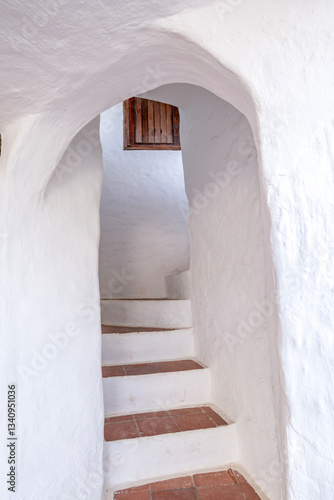 Obraz na płótnie Minimalist stairway with a rustic arch and terra cotta tiles. The beautiful town of Binibeca on Menorca. Narrow streets and white walls of houses with wooden elements, Mediterranean architecture w salonie