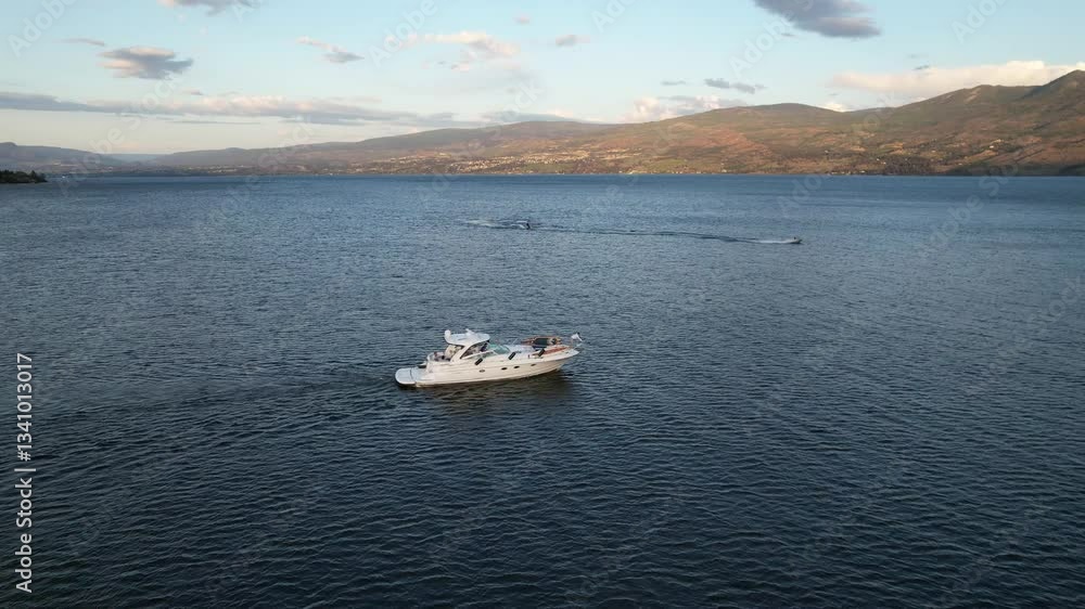 A stunning aerial drone shot of a luxury yacht cruising on a peaceful lake, surrounded by breathtaking mountain scenery. A stunning aerial drone shot of a luxury yacht cruising on a peaceful lake, surrounded by breathtaking mountain scenery.