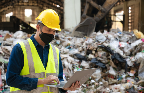 Fotografie An environmental engineer in safety gear works on a laptop at a recycling facility, managing waste processing and sustainability efforts