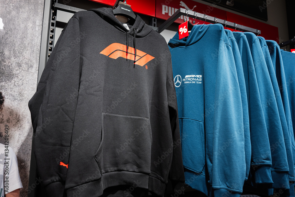 Obraz premium Variety of Puma F1 and AMG Petronas branded hoodies displayed on racks in a retail store