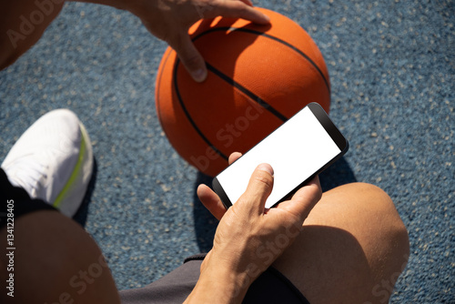 Obraz na płótnie Basketball player using smartphone and texting social media during game interval, Outdoor training. Top view. Close up. w salonie