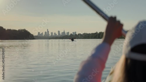 A woman paddling on a kayak on Vistula river with Warsaw cityscape in the background during sunset