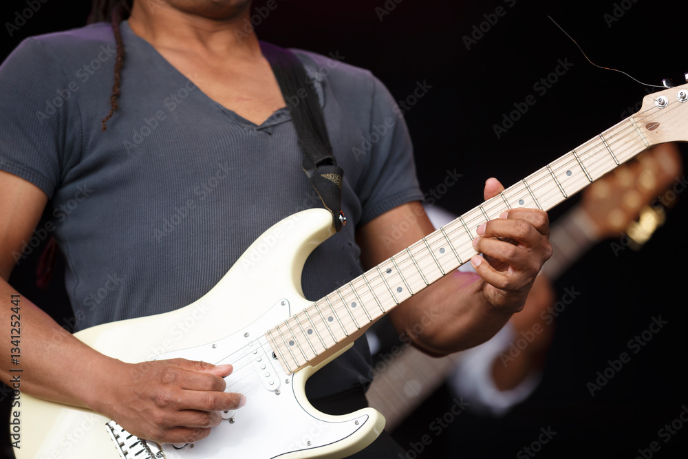Obraz premium Musician performs live on stage during an outdoor concert showcasing skillful guitar playing and engaging audience in summer festival atmosphere