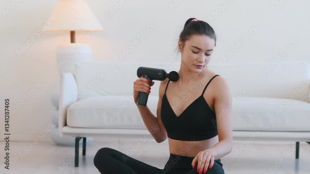 Wireless electric massager. Young woman with slim body type is indoors.