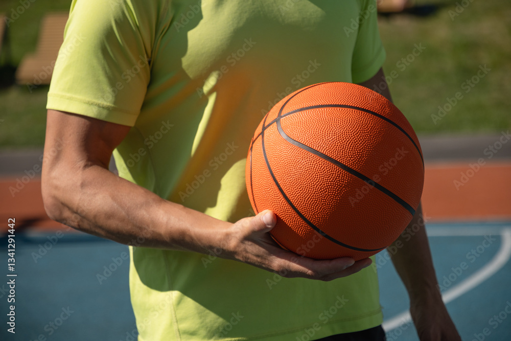 Basketball player, man holding orange ball on sports court. Sports goals competition game, champion outdoor workout. Close up. Copy space