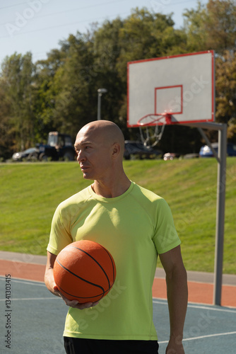 Obraz na płótnie Portrait of basketball player hold orange basketball ball on sports field. Outdoors. Basketball coach. w salonie