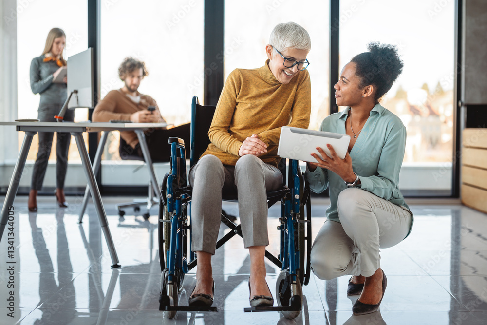 Disabled woman in wheelchair looking at computer, discussing startup project with interracial team Disabled woman in wheelchair looking at computer, discussing startup project with interracial team