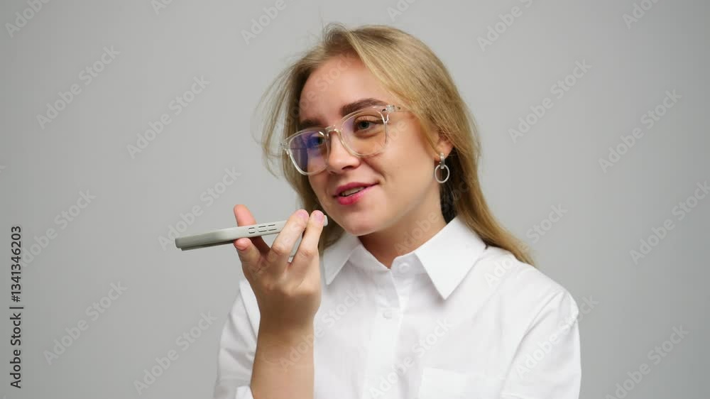 Woman with glasses interacting with a smartphone in an indoor environment, smiling happily.