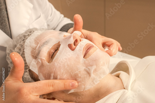 Fabric cosmetic mask. The secret of beauty, youth and radiant skin. Anti-aging skin care 40+. Cosmetic procedure. Skin hydration. Facial nutrition. Women's beauty. Beauty treatment. Beauty salon.
