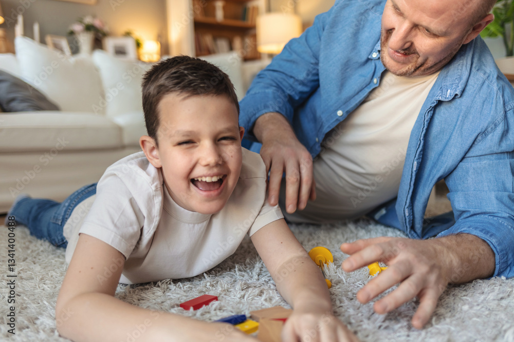 Obraz premium Loving young Caucasian dad sit on floor build with wooden blocks with small son, playful father have fun have construct tower from bricks cubes with little boy at home.