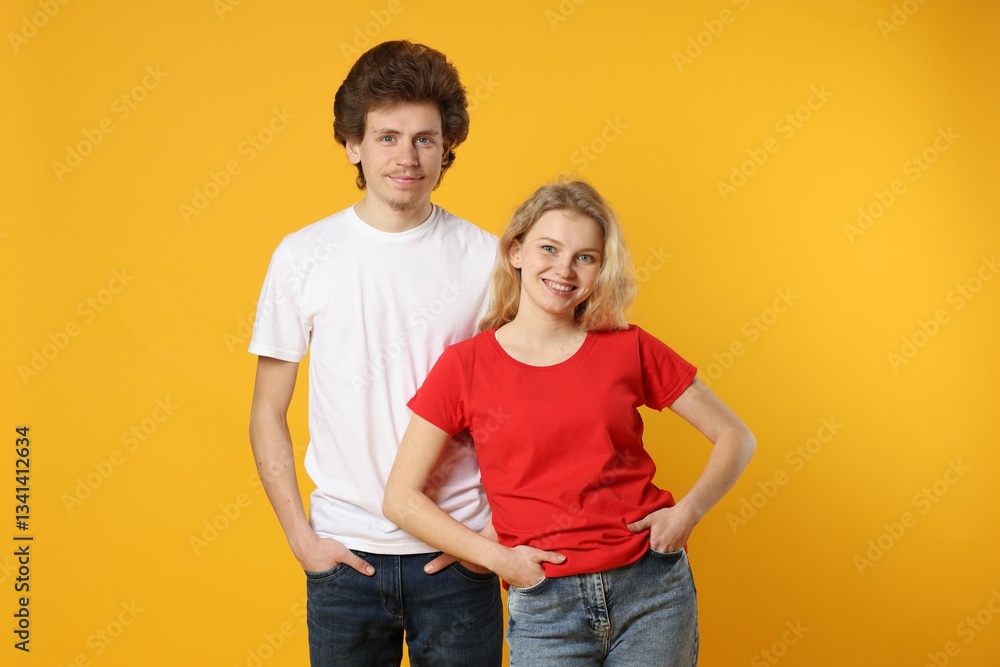 Young woman and man wearing blank t-shirts on orange background. Mockup for design Young woman and man wearing blank t-shirts on orange background. Mockup for design