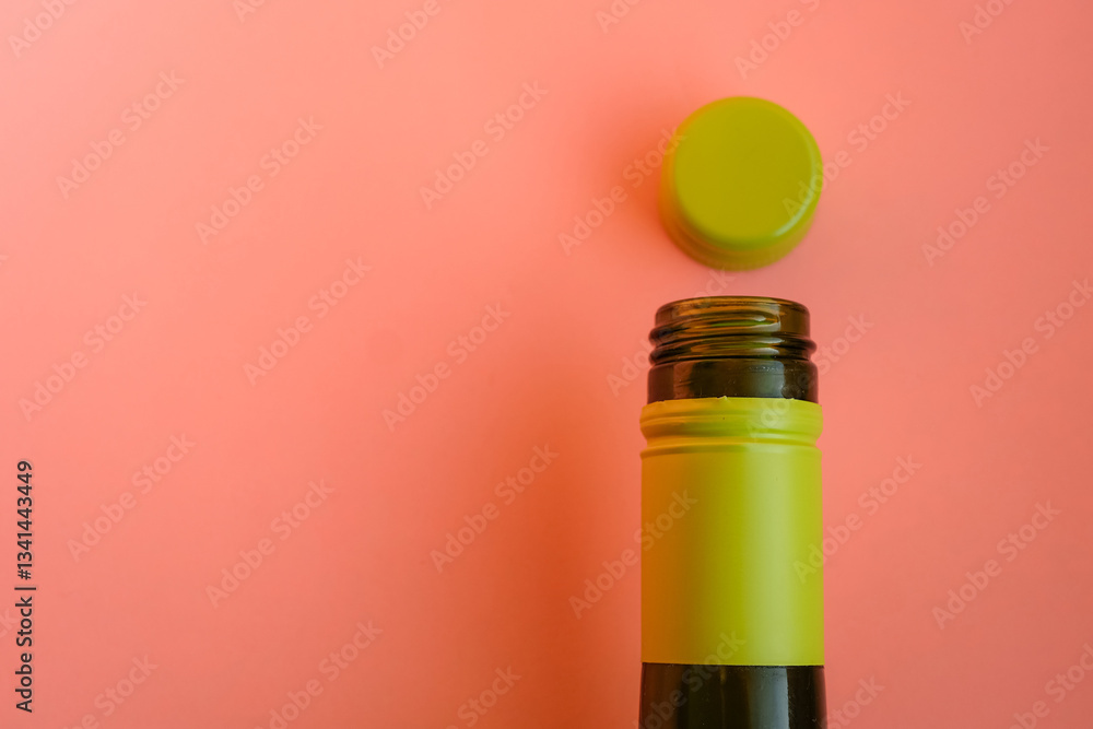 Fototapeta premium Green glass bottle with a lime green screw cap against a soft peach color background. Minimalism. Wine, and packaging design. Copy space.