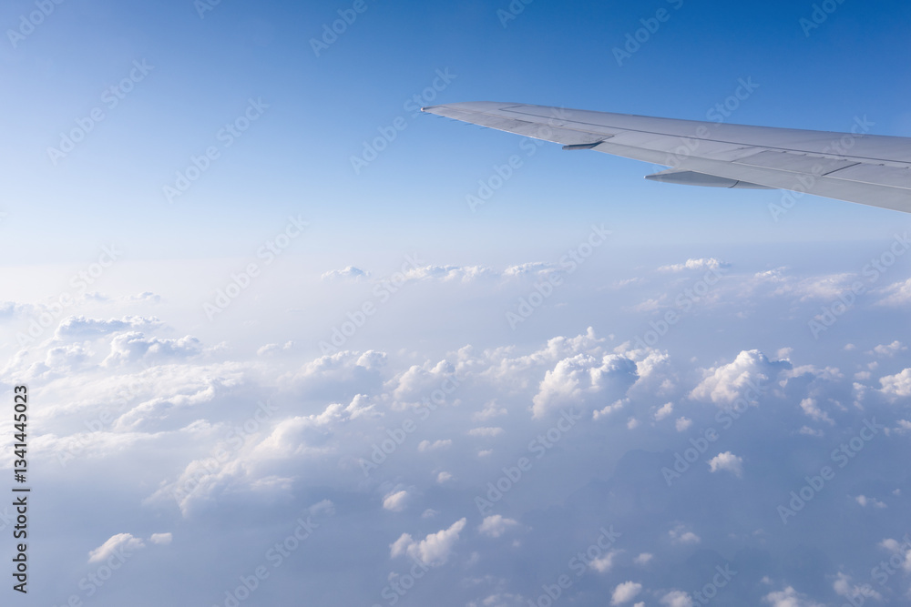 The background of a clear blue sky with white light clouds under the wing of an airliner carrying its passengers on a journey to distant lands. A background for traveling and a free empty space for The background of a clear blue sky with white light clouds under the wing of an airliner carrying its passengers on a journey to distant lands. A background for traveling and a free empty space for
