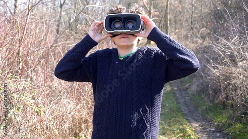Obraz na płótnie 10 year old boy with 3d AI virtual reality headset viewer in nature immerses himself in an immersive visual experience with reality augmented by artificial intelligence w salonie