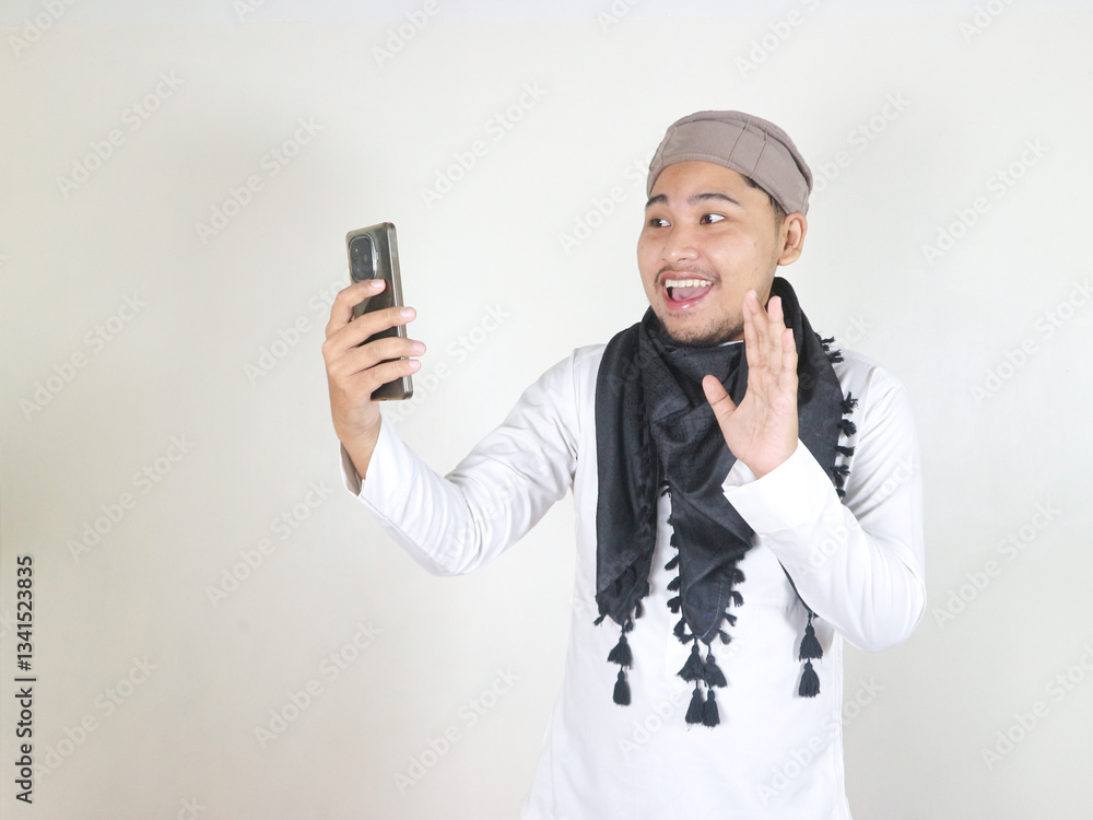 Fototapeta premium Handsome Asian Muslim man wearing black turban or shemagh showing dislike gesture by lowering thumbs down