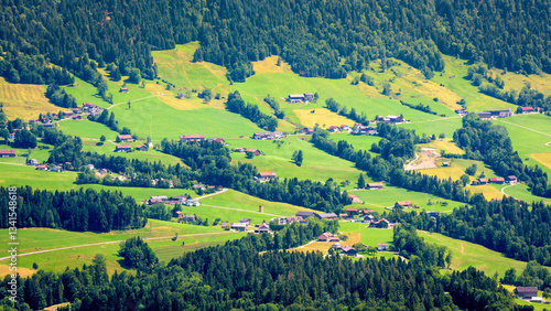 Obraz na płótnie Scenic aerial view of lush green valley with houses and forested hills in summer landscape w salonie