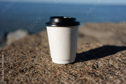 White coffee cup mockup on rocks and sea background. High quality photo