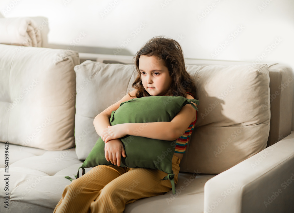 Child sitting alone on sofa feeling stressed unhappy, sad and depress. Little girl embracing pillow. Child sitting alone on sofa feeling stressed unhappy, sad and depress. Little girl embracing pillow.