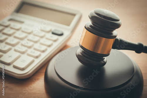Gavel hammer judge and white calculator on wooden table background. Tax law, financial law or regulation, creative accounting, corruption, bribe, bankruptcy, penalty and so on concept.