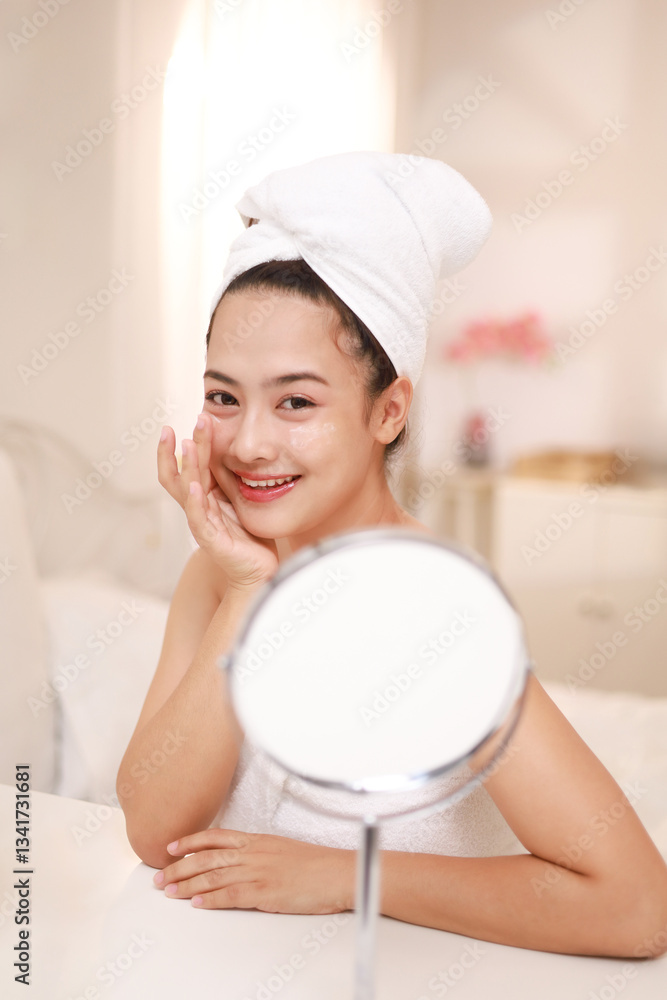 Smiling young woman applying cream on her face. Skin care, moisturizing, healthy and glowing skin. Smiling young woman applying cream on her face. Skin care, moisturizing, healthy and glowing skin.