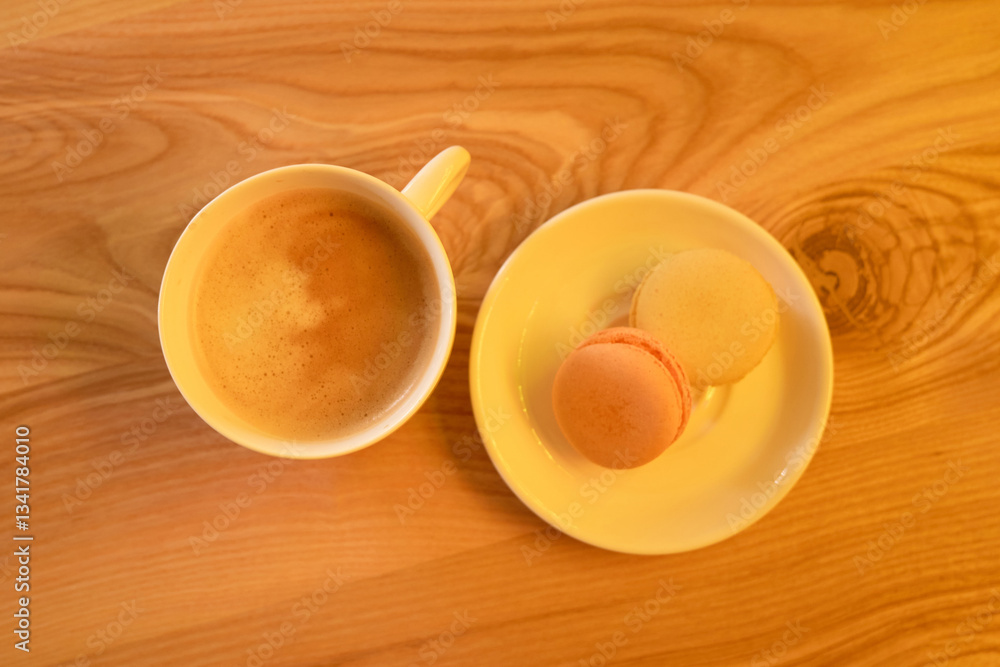 A cup of steaming coffee sits alongside a plate of colorful macarons on a polished wooden table. The warm ambiance is perfect for an afternoon treat at a local cafe A cup of steaming coffee sits alongside a plate of colorful macarons on a polished wooden table. The warm ambiance is perfect for an afternoon treat at a local cafe