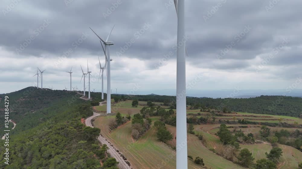 Aerial view of a wind farm on rolling hills under an overcast sky. Renewable energy landscape. Aerial view of a wind farm on rolling hills under an overcast sky. Renewable energy landscape.