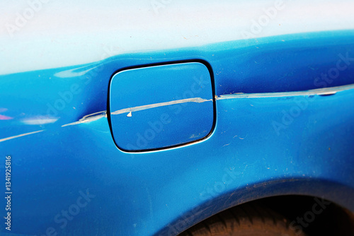 Obraz na płótnie Scratched fuel door on rear side of car, paint damage and surface imperfections on vehicle's body, collision aftermath, wear and tear. Visible scratches, paint damage on car fuel door. Selective focus w salonie