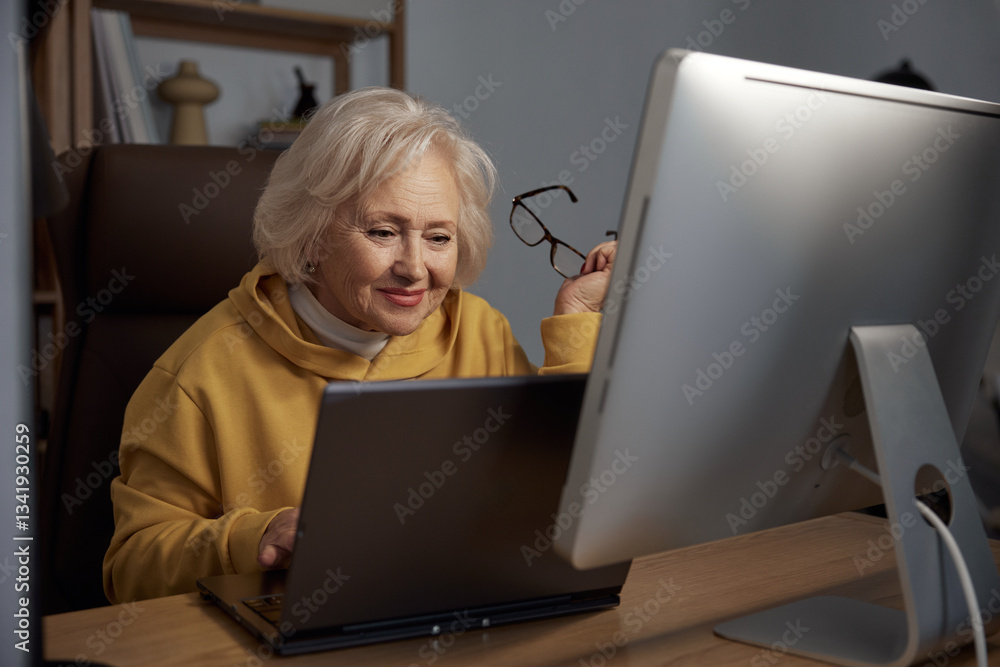 Focused elderly woman using desktop computer at home portrait shot