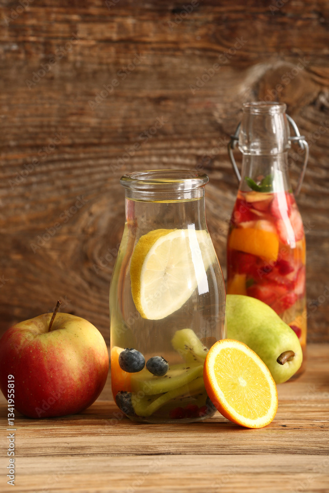 Bottles of infused water with different sliced fruits on wooden table Bottles of infused water with different sliced fruits on wooden table