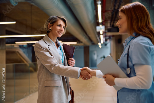 Foto Happy nurse handshaking with businesswoman in hospital.