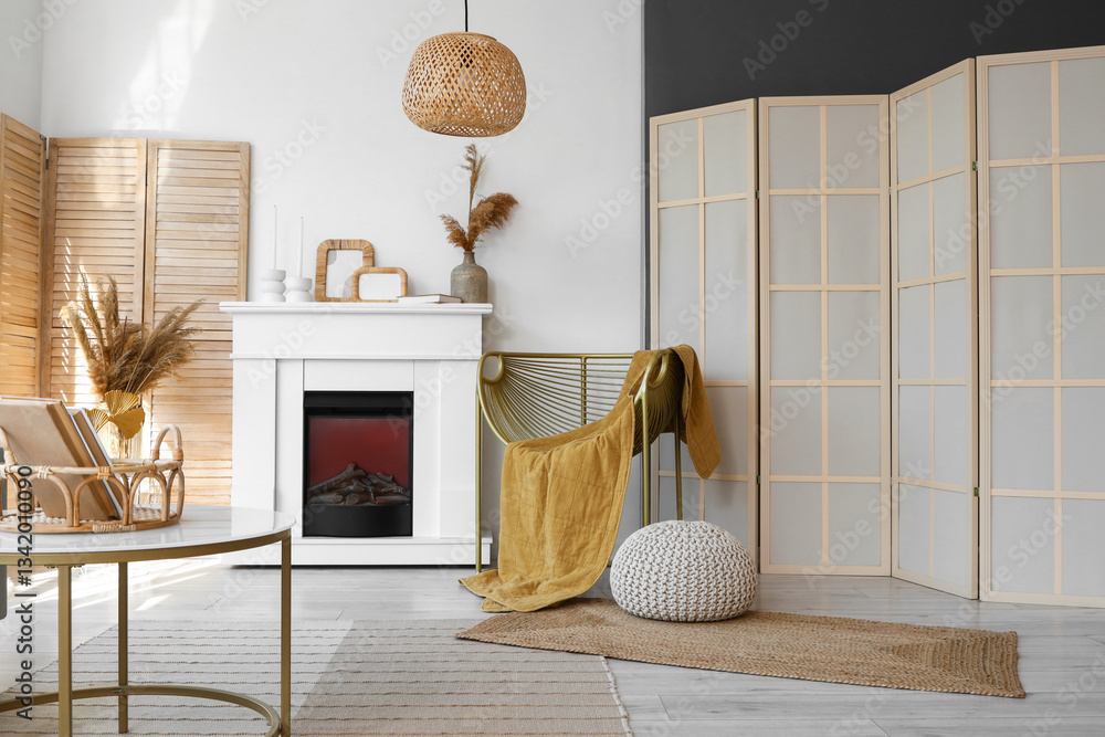 Fototapeta premium Interior of light living room with armchair, fireplace and folding screen