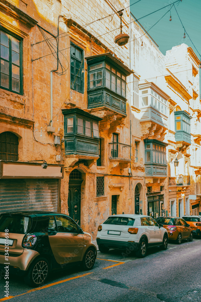 Fototapeta premium Typical narrow streets with colorful balconies in VallettaTypical narrow streets with colorful balconies. Narrow streets with colourful window boxes in Valetta, MaltaTraditional Maltese balconies in V