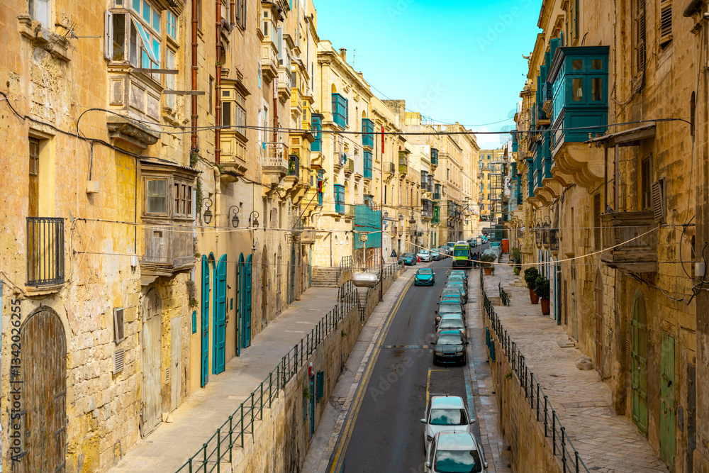Obraz premium Typical narrow streets with colorful balconies in VallettaTypical narrow streets with colorful balconies. Narrow streets with colourful window boxes in Valetta, Malta Traditional Maltese balconies