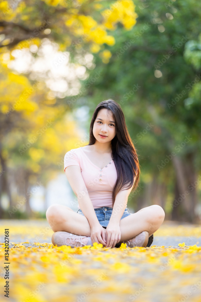 Portrait cute smiles Asian of attractive young teenage girl in Beautiful blooming Yellow Golden Tabebuia Chrysotricha flowers with the park in spring day at Evening background in Thailand.