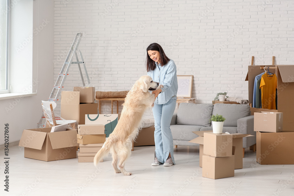 Fototapeta premium Young happy woman and cute Labrador dog with boxes having fun on moving day at home