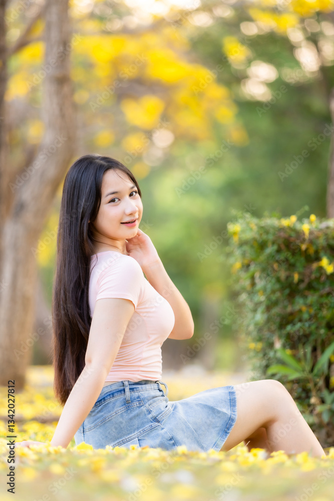 Portrait cute smiles Asian of attractive young teenage girl in Beautiful blooming Yellow Golden Tabebuia Chrysotricha flowers with the park in spring day at Evening background in Thailand.