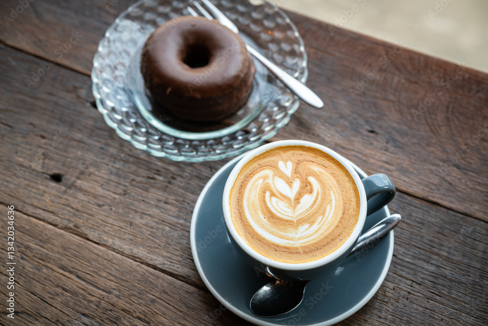 Hot coffee latte with latte art milk foam in cup mug and Homemade chocolate Donut on wood desk on top view. As breakfast In a coffee shop at the cafe,during business work concept,vintage style