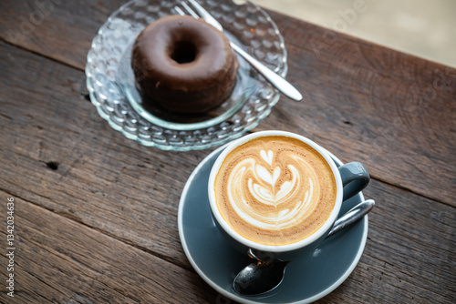 Obraz na płótnie Hot coffee latte with latte art milk foam in cup mug and Homemade chocolate Donut on wood desk on top view. As breakfast In a coffee shop at the cafe,during business work concept,vintage style w salonie