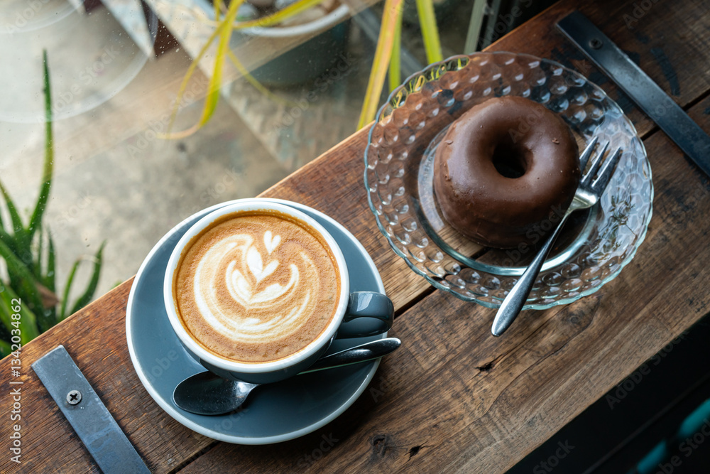 Hot coffee latte with latte art milk foam in cup mug and Homemade chocolate Donut on wood desk on top view. As breakfast In a coffee shop at the cafe,during business work concept,vintage style