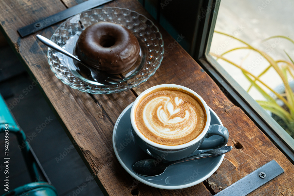 Hot coffee latte with latte art milk foam in cup mug and Homemade chocolate Donut on wood desk on top view. As breakfast In a coffee shop at the cafe,during business work concept,vintage style