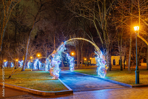 Decorative arches decorated with flowers and illumination in the city park. Evening lighting. Kharkov, Shevchenko city garden.