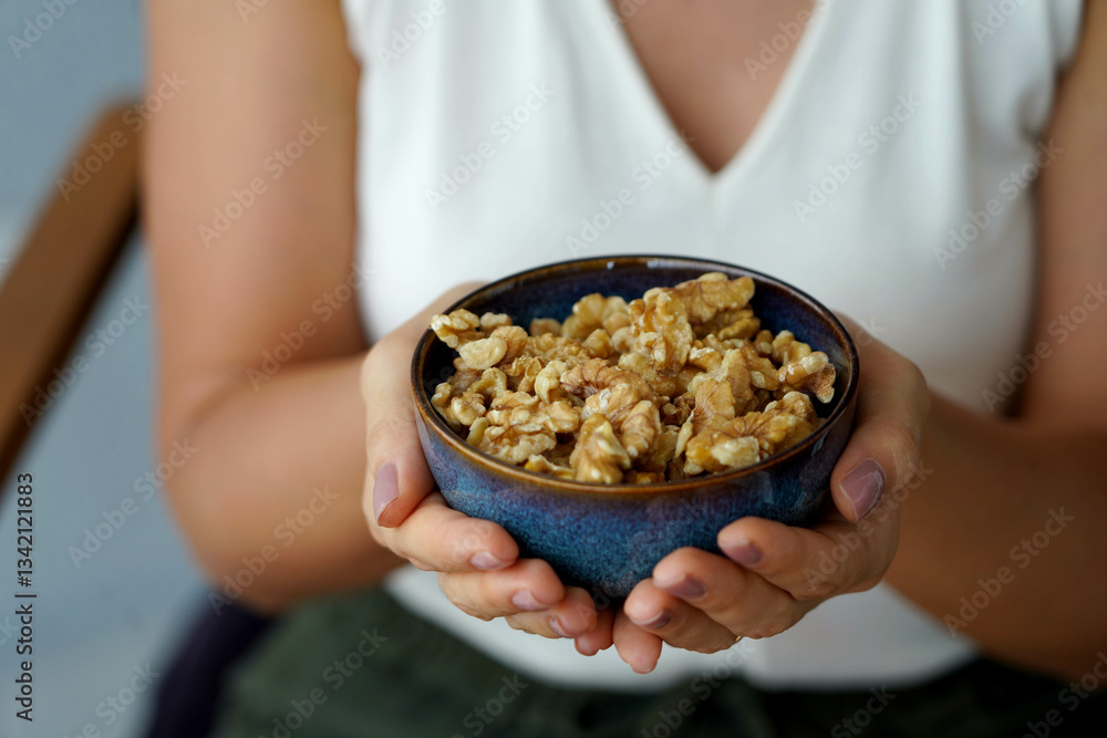 Female hands showing a bowl full of walnuts