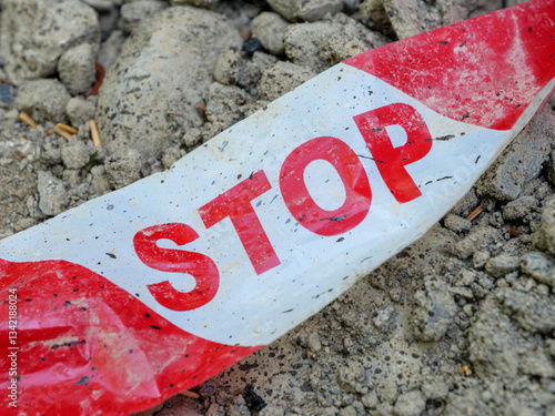 Safety tape with STOP warning placed on uneven ground at a construction site photo