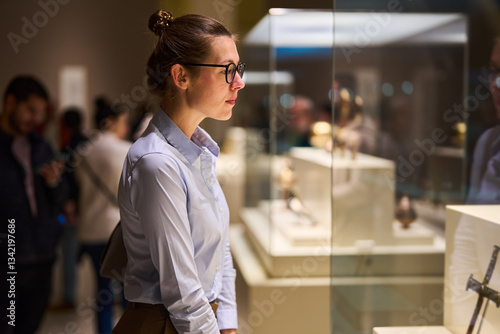 Billede på lærred visitor in historical museum looking at art object