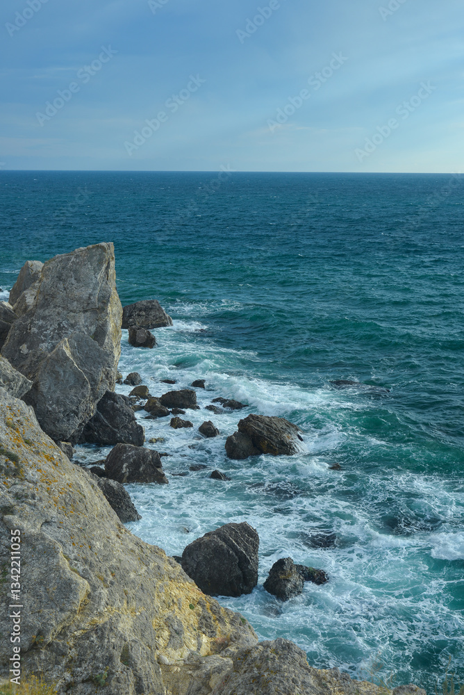 Waves of the Black Sea crash on a rocky shore on a sunny day in Crimea