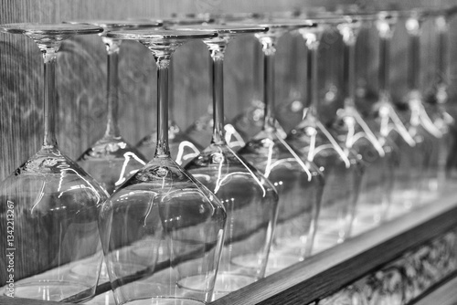 Transparent drinking glasses perfectly lined up on wooden shelves in a restaurant