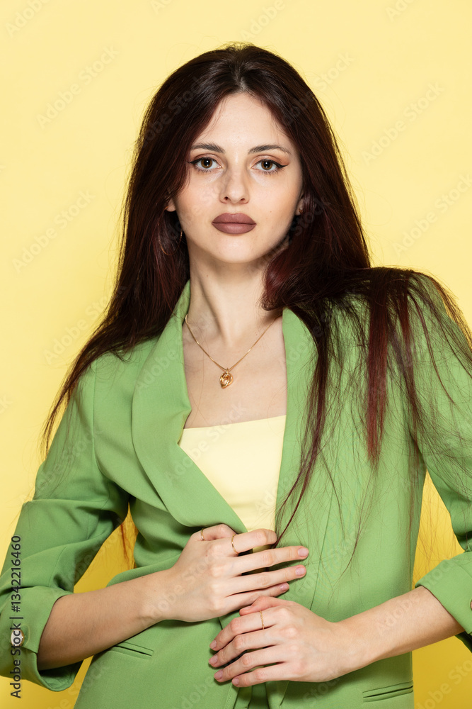 Fashion portrait of beautiful model in green suit against yellow background