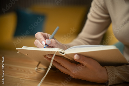 A person writes thoughtfully in a journal while seated in a warm, inviting space. The act of journaling offers a moment of reflection, creativity, and personal expression.